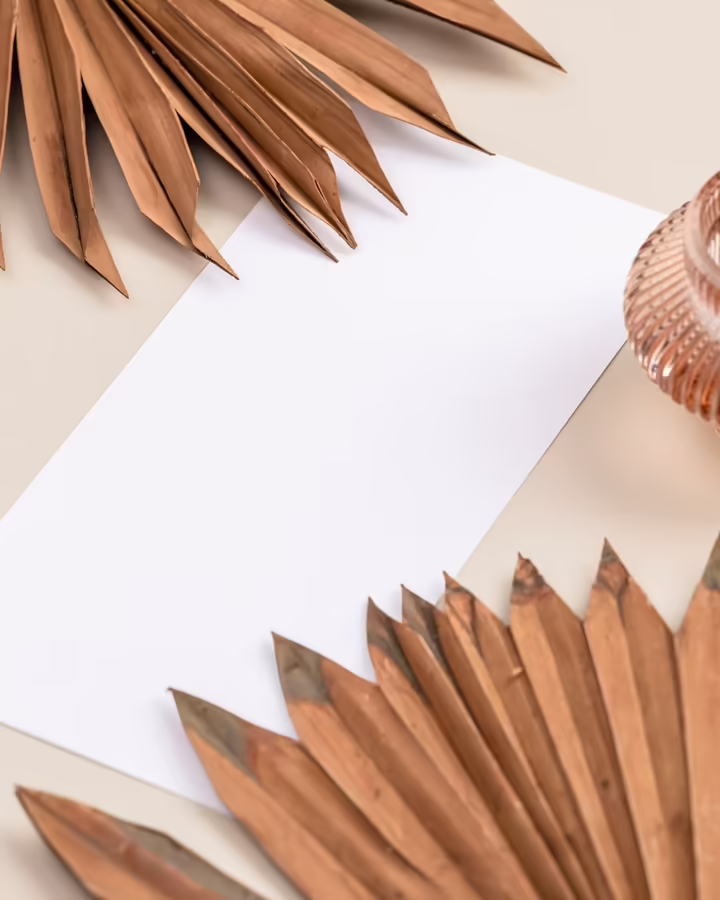 Feuilles séchées posées près d'un papier blanc et d'un vase en verre